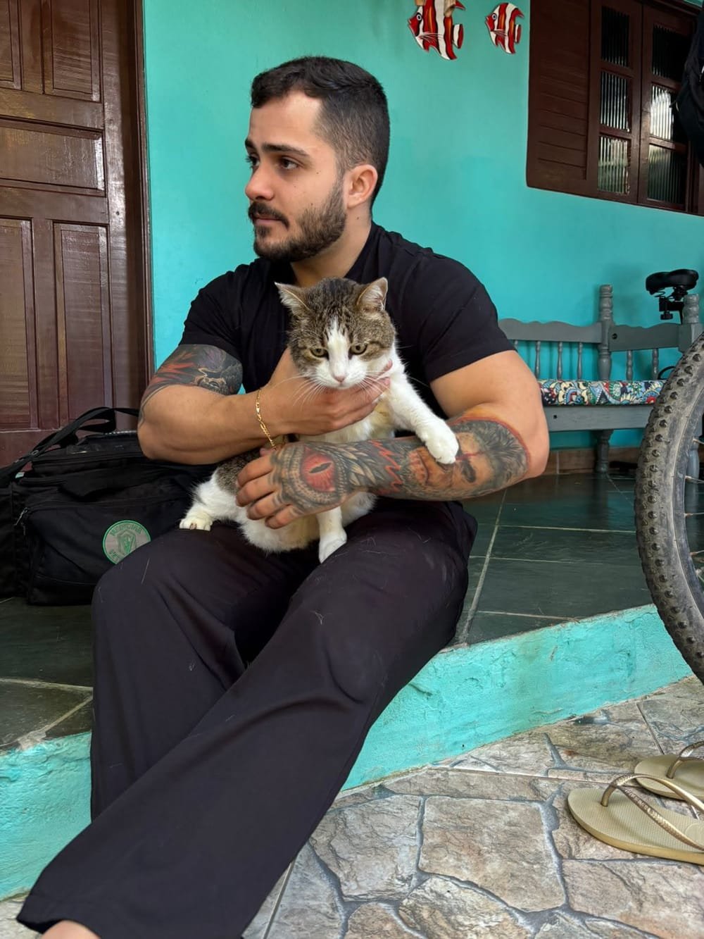 Veterinário segurando um gato no colo durante atendimento domiciliar na varanda