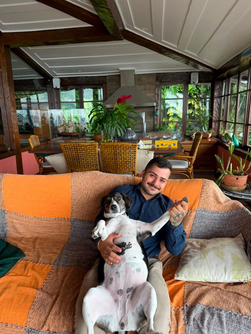 Veterinário sorrindo com um cachorro no colo durante atendimento domiciliar